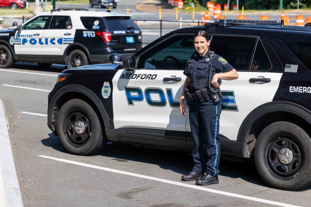 Female police officer standing in front of a cruiser.